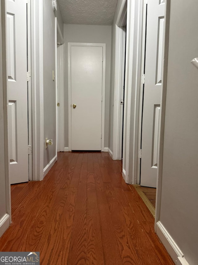 hall featuring light hardwood / wood-style floors and a textured ceiling