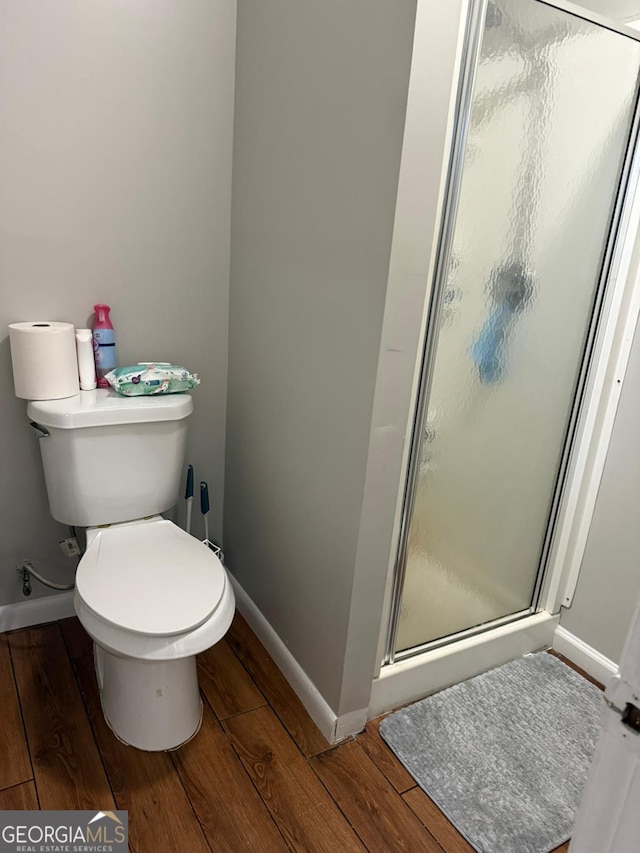 bathroom featuring toilet, an enclosed shower, and hardwood / wood-style floors