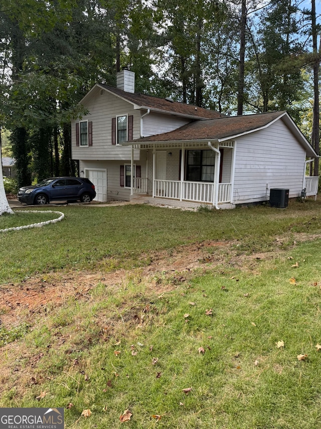 tri-level home featuring a front yard, a porch, central AC unit, and a garage