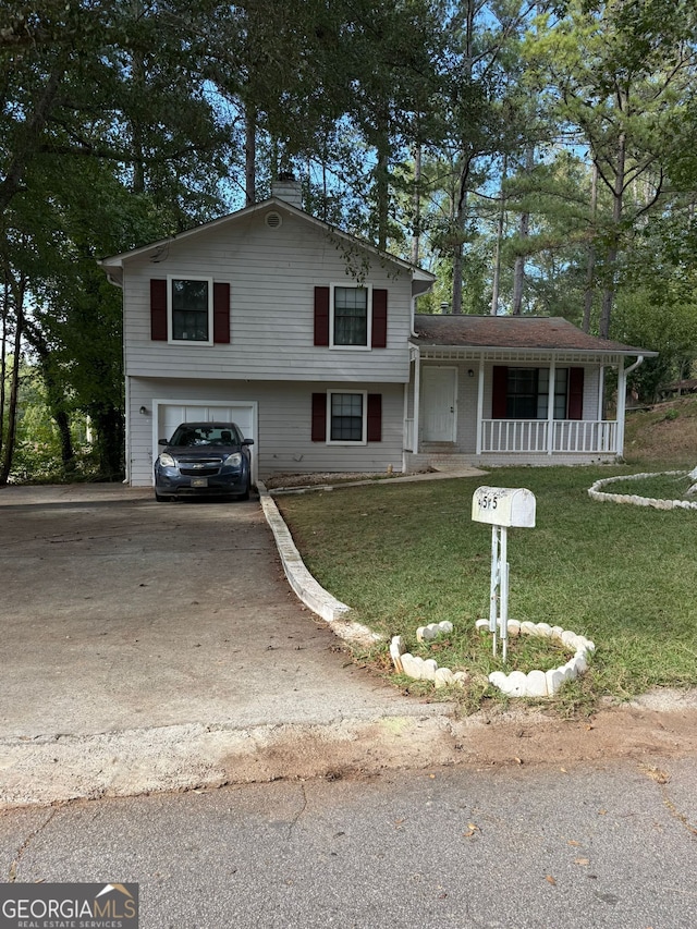 tri-level home with covered porch, a front lawn, and a garage