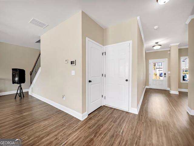 foyer entrance featuring crown molding and dark hardwood / wood-style floors