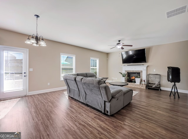 living room featuring ceiling fan with notable chandelier, dark wood-type flooring, and a fireplace