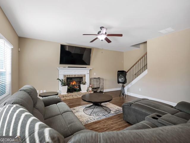 living room featuring hardwood / wood-style floors, a brick fireplace, and ceiling fan