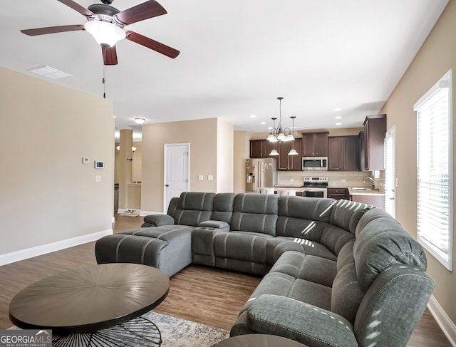 living room featuring sink, dark wood-type flooring, and ceiling fan with notable chandelier