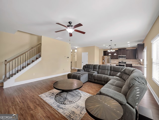 living room featuring sink, dark hardwood / wood-style floors, and ceiling fan with notable chandelier