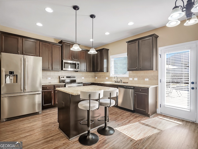 kitchen featuring a center island, appliances with stainless steel finishes, hanging light fixtures, and plenty of natural light