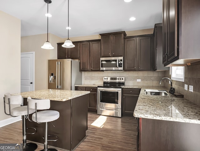 kitchen with appliances with stainless steel finishes, sink, a kitchen island, dark hardwood / wood-style flooring, and decorative light fixtures