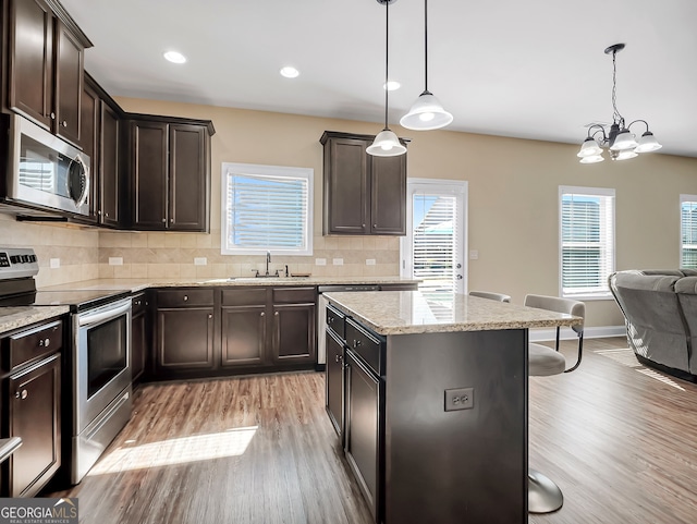 kitchen with sink, a breakfast bar, decorative light fixtures, and stainless steel appliances