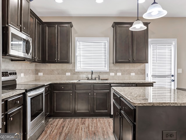 kitchen featuring light hardwood / wood-style flooring, stainless steel appliances, sink, dark brown cabinetry, and decorative light fixtures