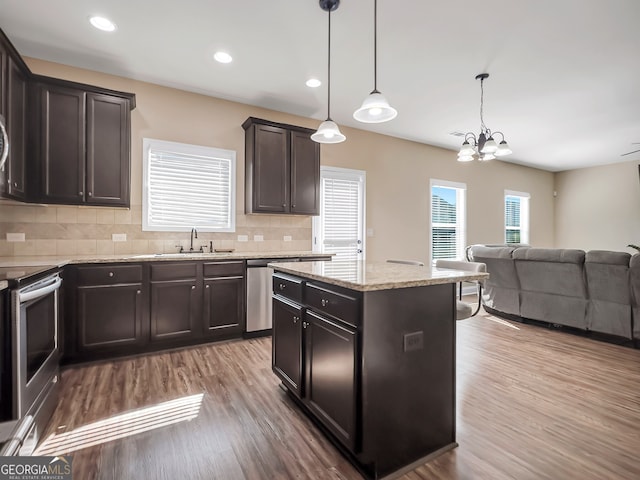 kitchen with sink, a kitchen island, hanging light fixtures, hardwood / wood-style flooring, and decorative backsplash