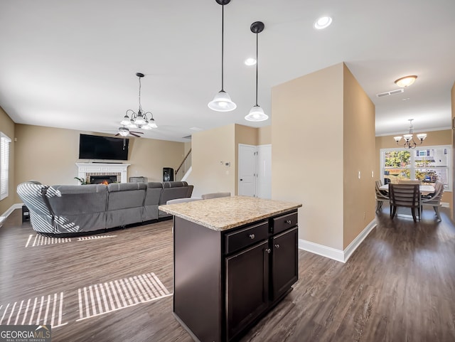 kitchen with dark hardwood / wood-style floors, a kitchen island, pendant lighting, and an inviting chandelier