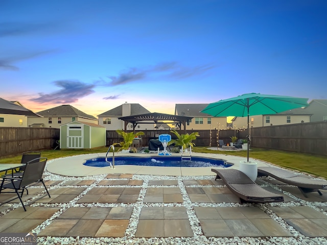 pool at dusk with a yard, a storage shed, and a patio area