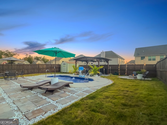 pool at dusk with a yard, a patio area, and a shed