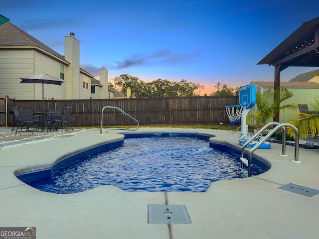 pool at dusk featuring a patio area