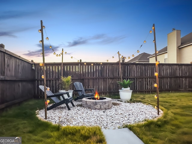 yard at dusk featuring an outdoor fire pit