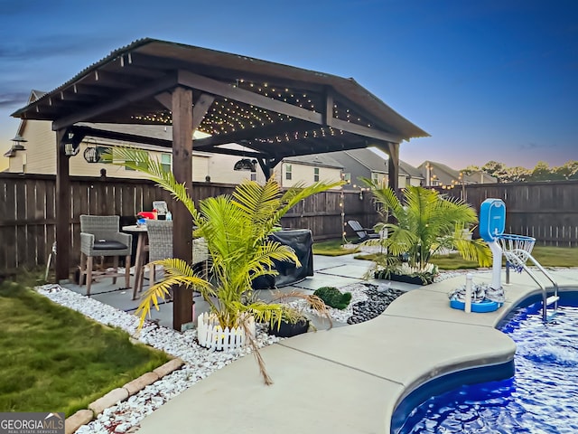 patio terrace at dusk with a gazebo and a fenced in pool