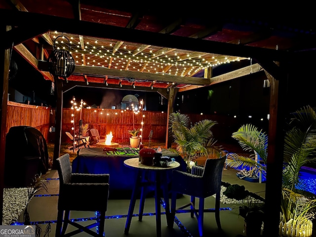 patio at night with a fire pit and a pergola