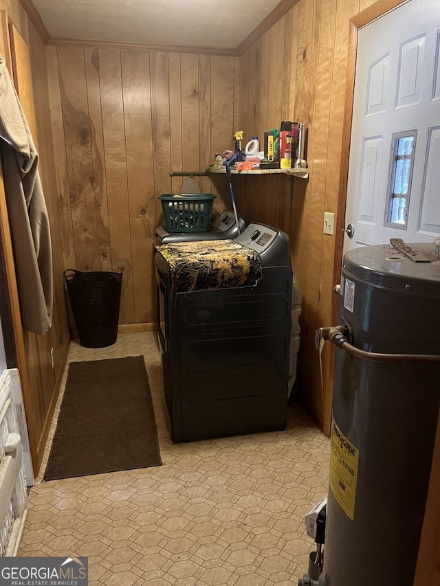 laundry room featuring water heater, wooden walls, and washer and dryer