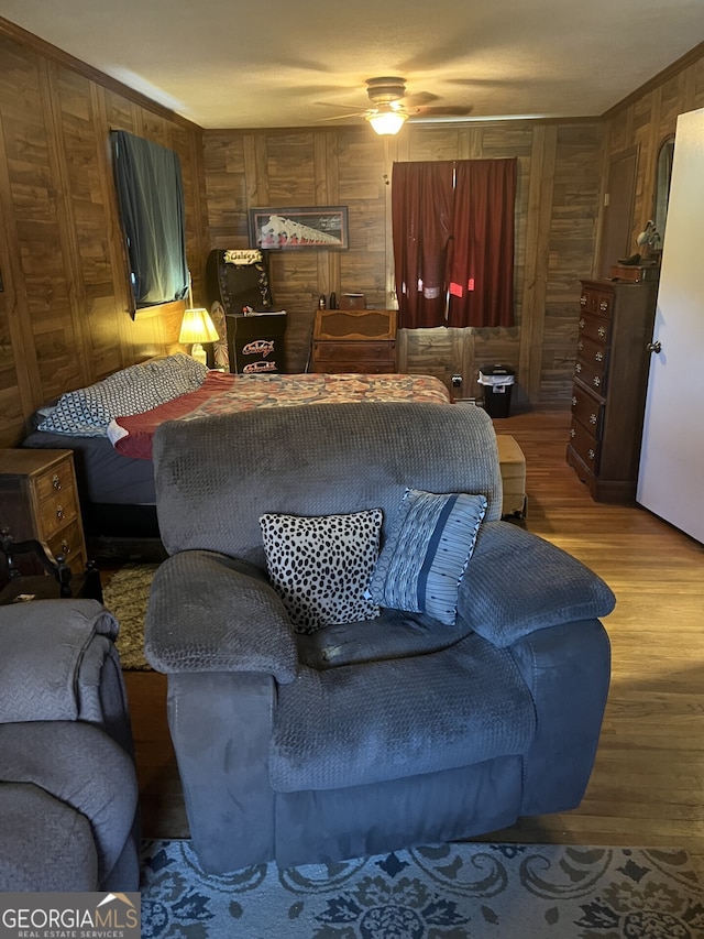 living room featuring wood walls, wood-type flooring, and ceiling fan