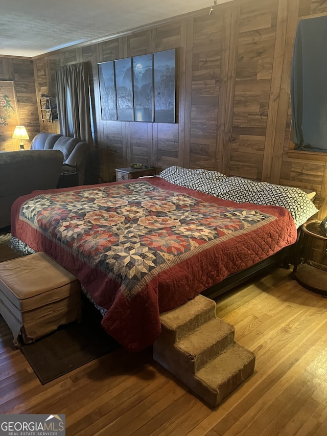 bedroom with hardwood / wood-style floors and wooden walls