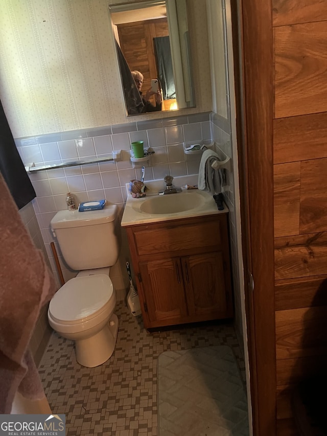 bathroom with vanity, toilet, tile patterned floors, and tile walls