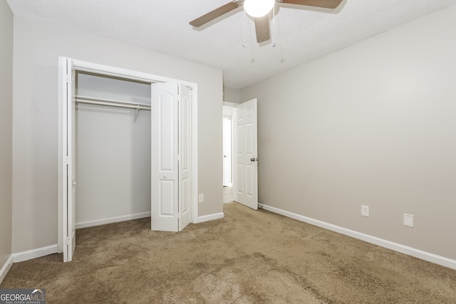 unfurnished bedroom featuring a closet, a textured ceiling, carpet flooring, and ceiling fan