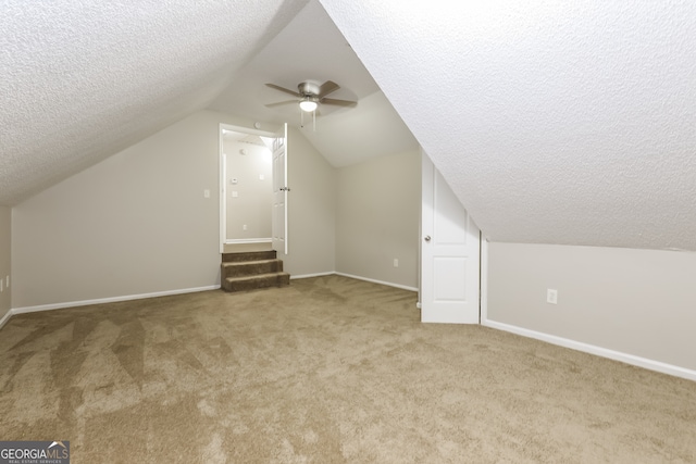 additional living space with light carpet, a textured ceiling, ceiling fan, and vaulted ceiling