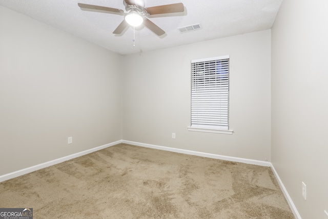 carpeted spare room with ceiling fan and a textured ceiling