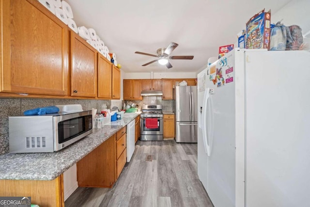 kitchen with tasteful backsplash, light stone countertops, ceiling fan, stainless steel appliances, and light hardwood / wood-style flooring