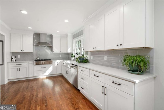 kitchen with wall chimney exhaust hood, dark wood-type flooring, white cabinets, and stainless steel appliances