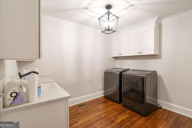 laundry area featuring dark hardwood / wood-style floors, crown molding, cabinets, a chandelier, and washing machine and clothes dryer