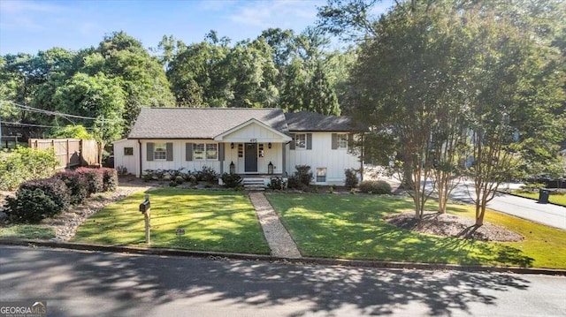 view of front of house with board and batten siding, a front lawn, and fence