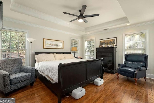 bedroom featuring ceiling fan, a raised ceiling, multiple windows, and dark hardwood / wood-style floors