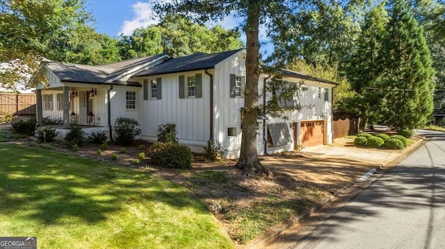 view of front facade with a front lawn, concrete driveway, board and batten siding, covered porch, and a garage
