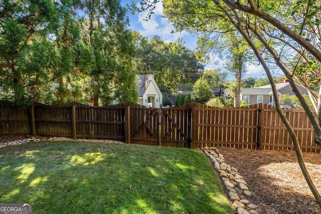 view of yard with a fenced backyard and a gate