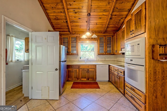 kitchen featuring vaulted ceiling with beams, decorative light fixtures, a wealth of natural light, and white appliances