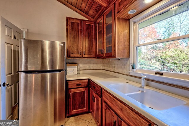 kitchen with wooden ceiling, sink, vaulted ceiling, light tile patterned flooring, and stainless steel refrigerator