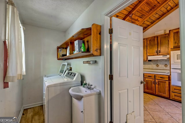 clothes washing area featuring sink, independent washer and dryer, light tile patterned floors, and wood ceiling