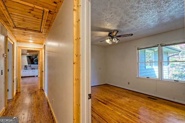 corridor with a textured ceiling, wood ceiling, and hardwood / wood-style flooring