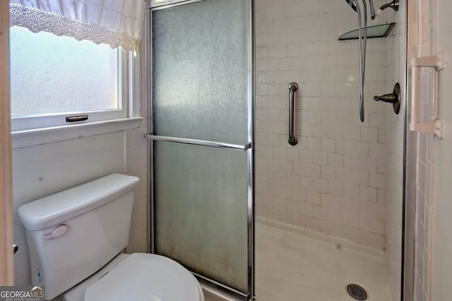 bathroom with toilet and a shower with door