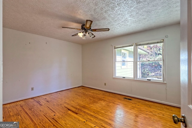 spare room with ceiling fan, a textured ceiling, and light wood-type flooring