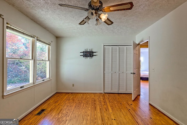 spare room with light hardwood / wood-style floors, a textured ceiling, and ceiling fan