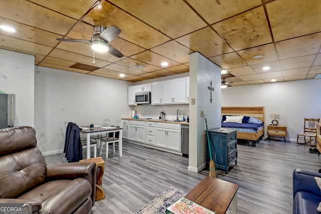 living room featuring sink, light wood-type flooring, and ceiling fan