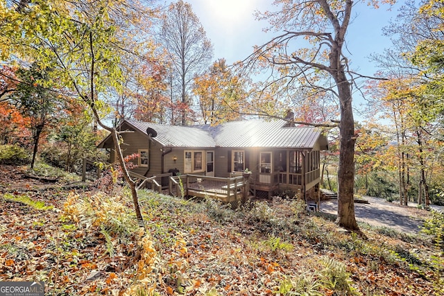 rear view of house featuring a wooden deck and a sunroom