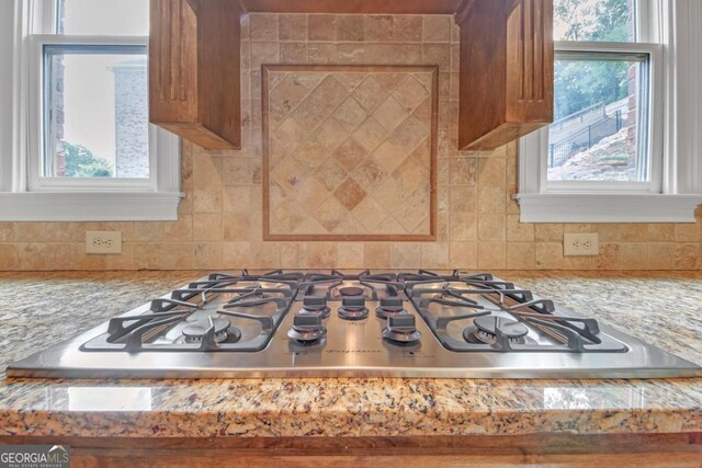 details with tasteful backsplash, light stone counters, and stainless steel gas cooktop