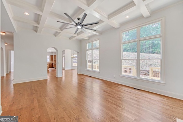 unfurnished living room featuring beamed ceiling, ceiling fan, a healthy amount of sunlight, and coffered ceiling