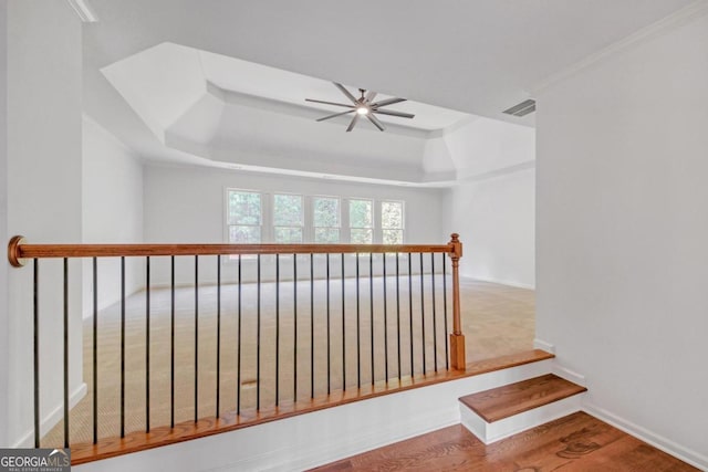 hallway featuring a tray ceiling, light hardwood / wood-style flooring, and ornamental molding