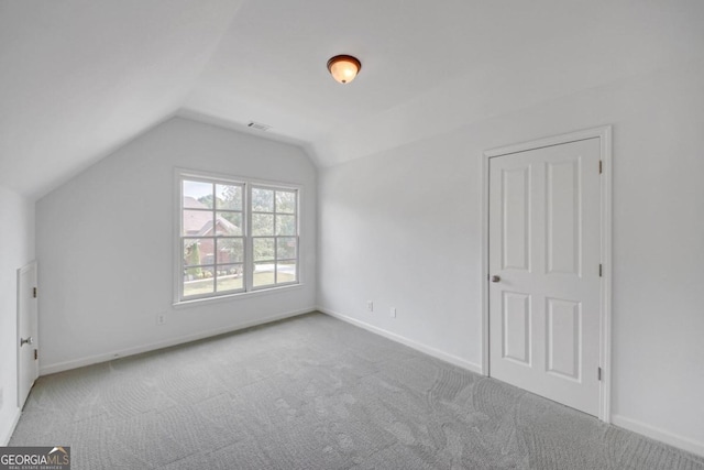 additional living space featuring light colored carpet and lofted ceiling