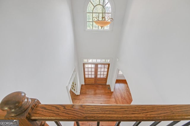 stairs with french doors and hardwood / wood-style flooring