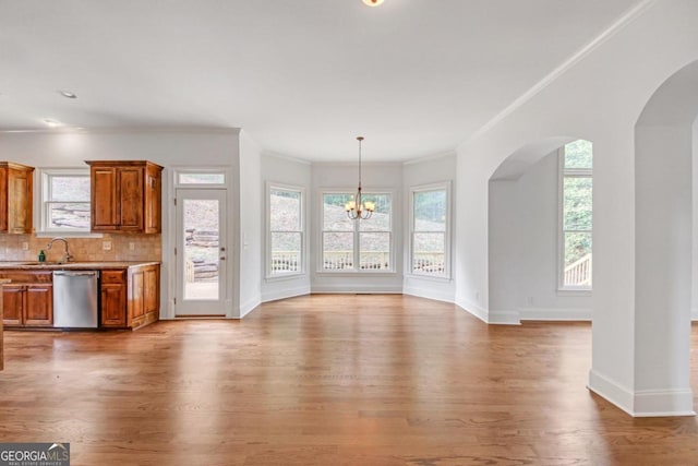 unfurnished living room with crown molding, sink, light wood-type flooring, and a notable chandelier